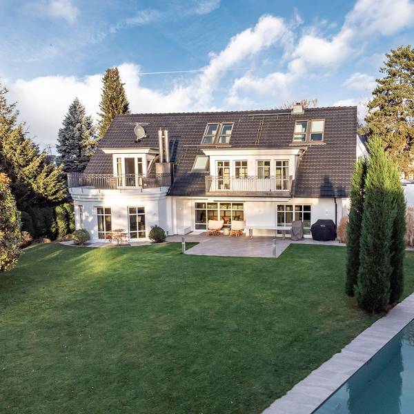 Außenansicht einer Luxus-Immobilie in Sankt Augustin, davor ein Garten mit Pool.