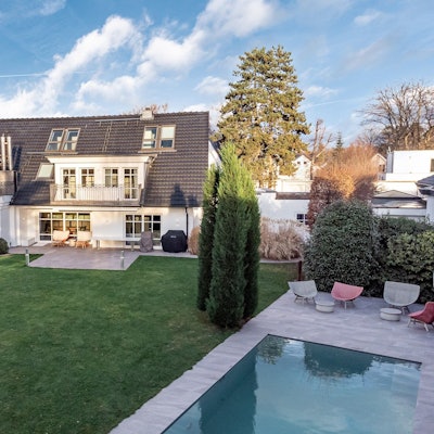 Außenansicht einer Luxus-Immobilie in Sankt Augustin, davor ein Garten mit Pool.