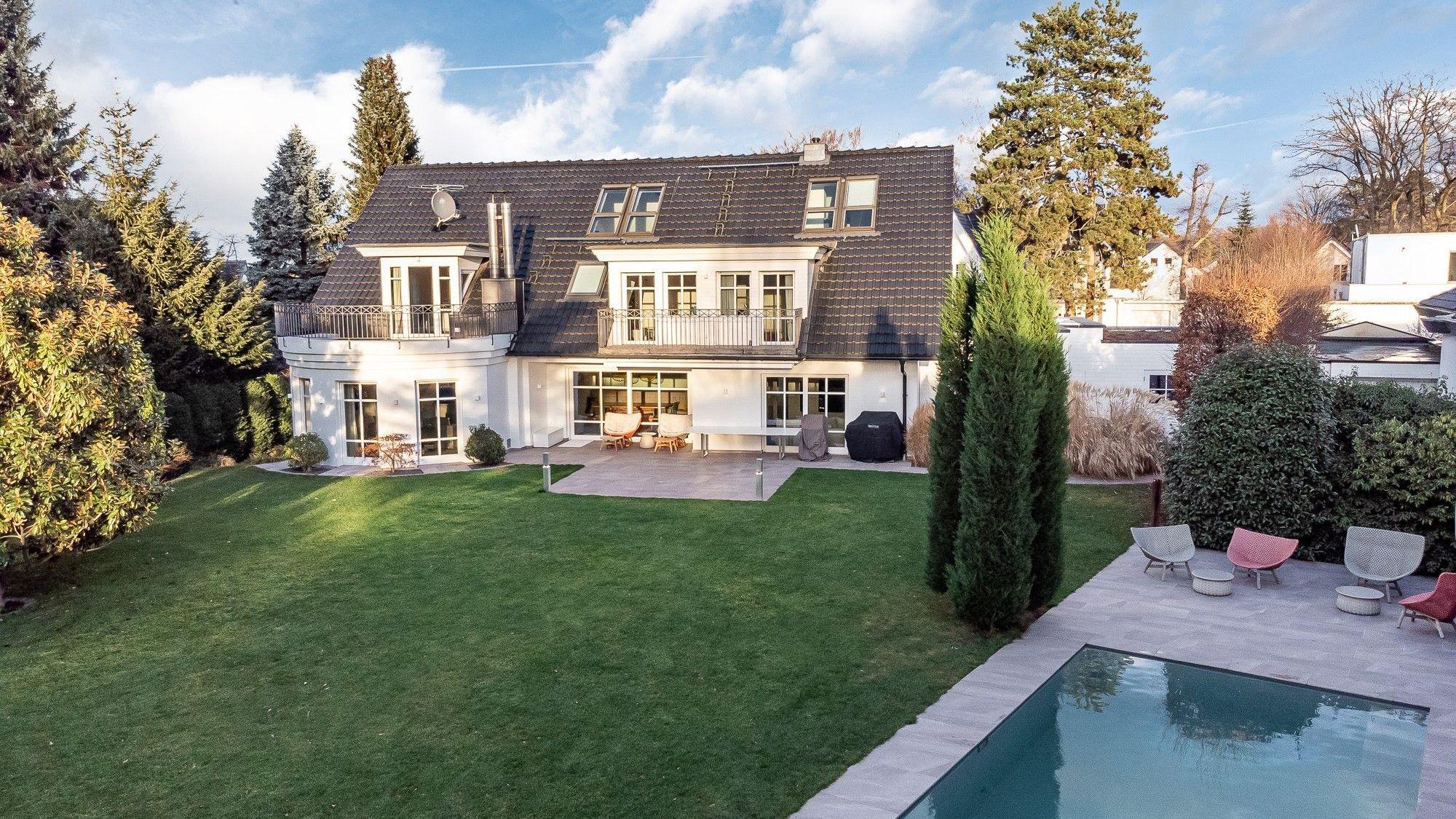 Außenansicht einer Luxus-Immobilie in Sankt Augustin, davor ein Garten mit Pool.