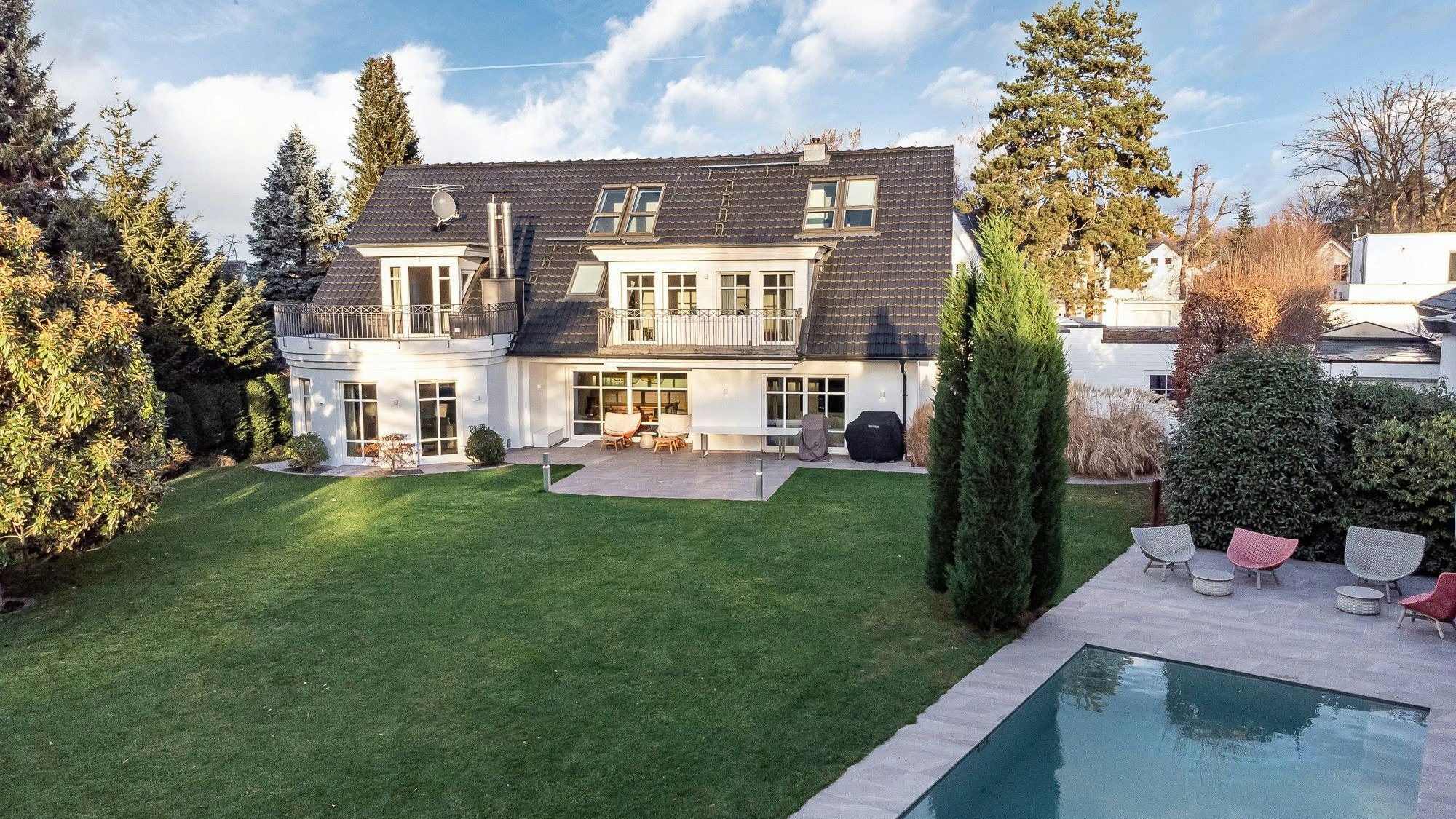 Außenansicht einer Luxus-Immobilie in Sankt Augustin, davor ein Garten mit Pool.