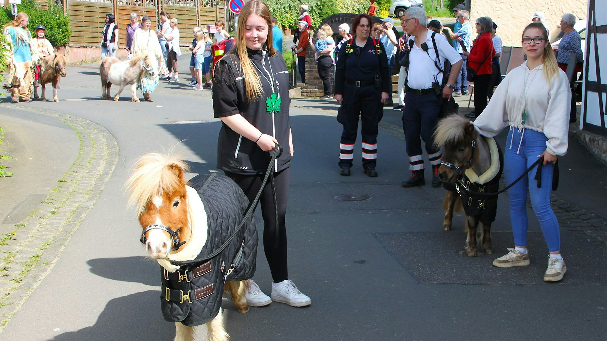 Die beiden jungen Teilnehmerinnen führen Ponys am Zügel, die kaum größer sind als ein großer Hund.