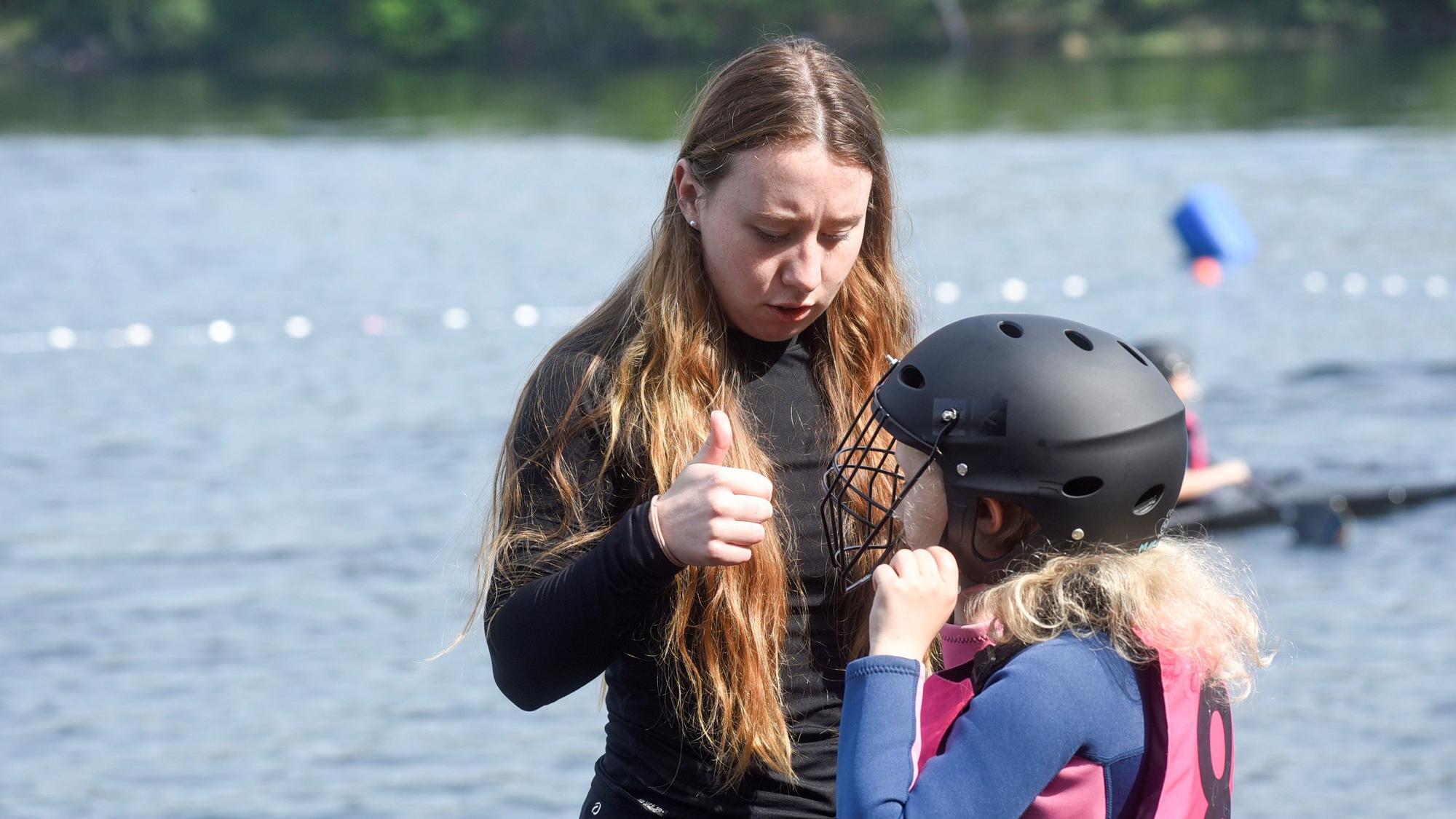 Trainerin merle Reimers und ein Kind mit einem Schutzhelm vor dem Liblarer See.