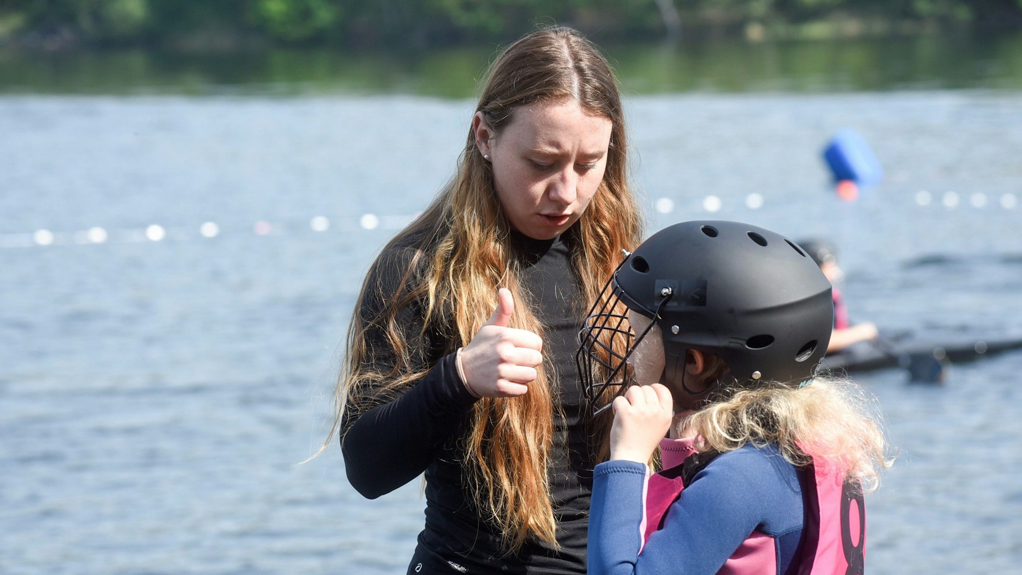 Trainerin merle Reimers und ein Kind mit einem Schutzhelm vor dem Liblarer See.