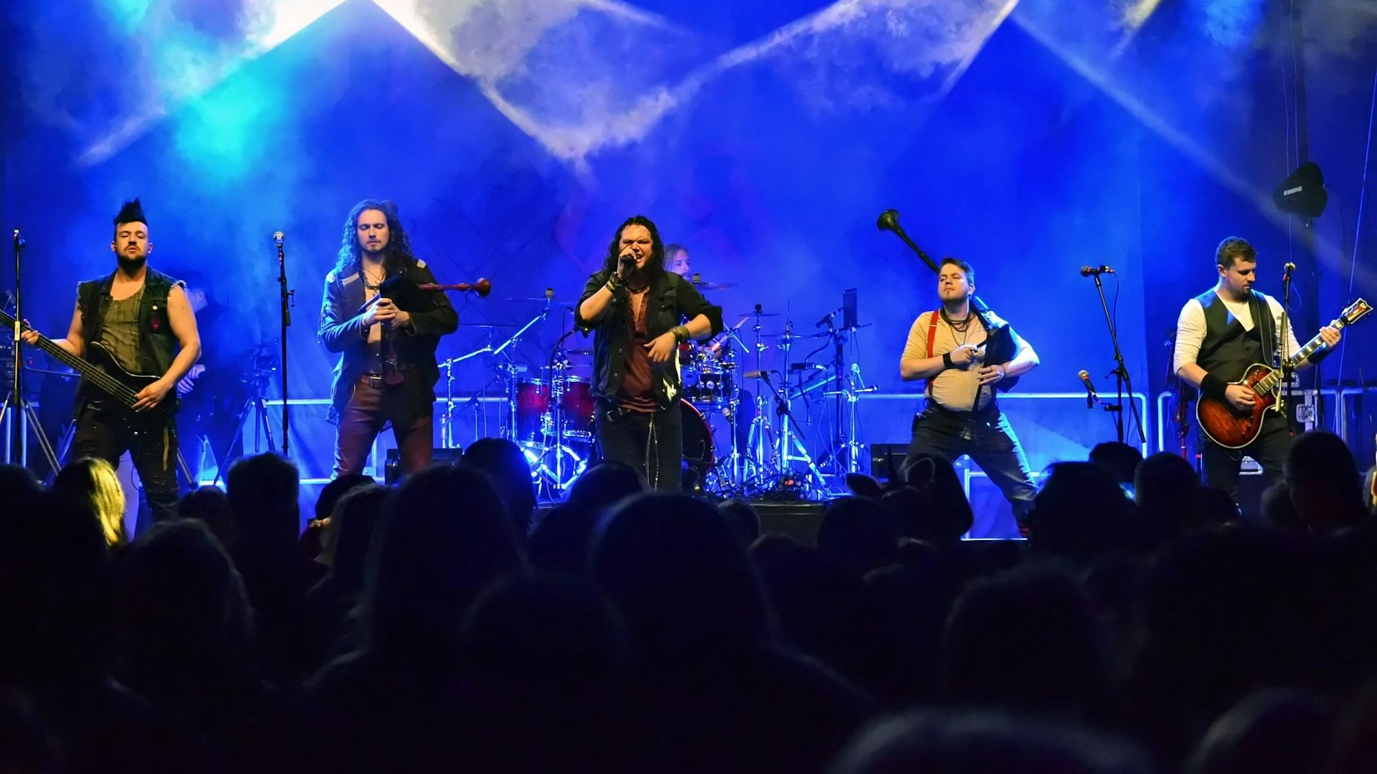 In blaues Licht getaucht, spielt eine Band auf der Bühne.