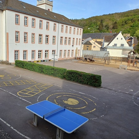 Das Bild zeigt den Blick auf die Grundschule mit dem Schulhof im Vordergrund.