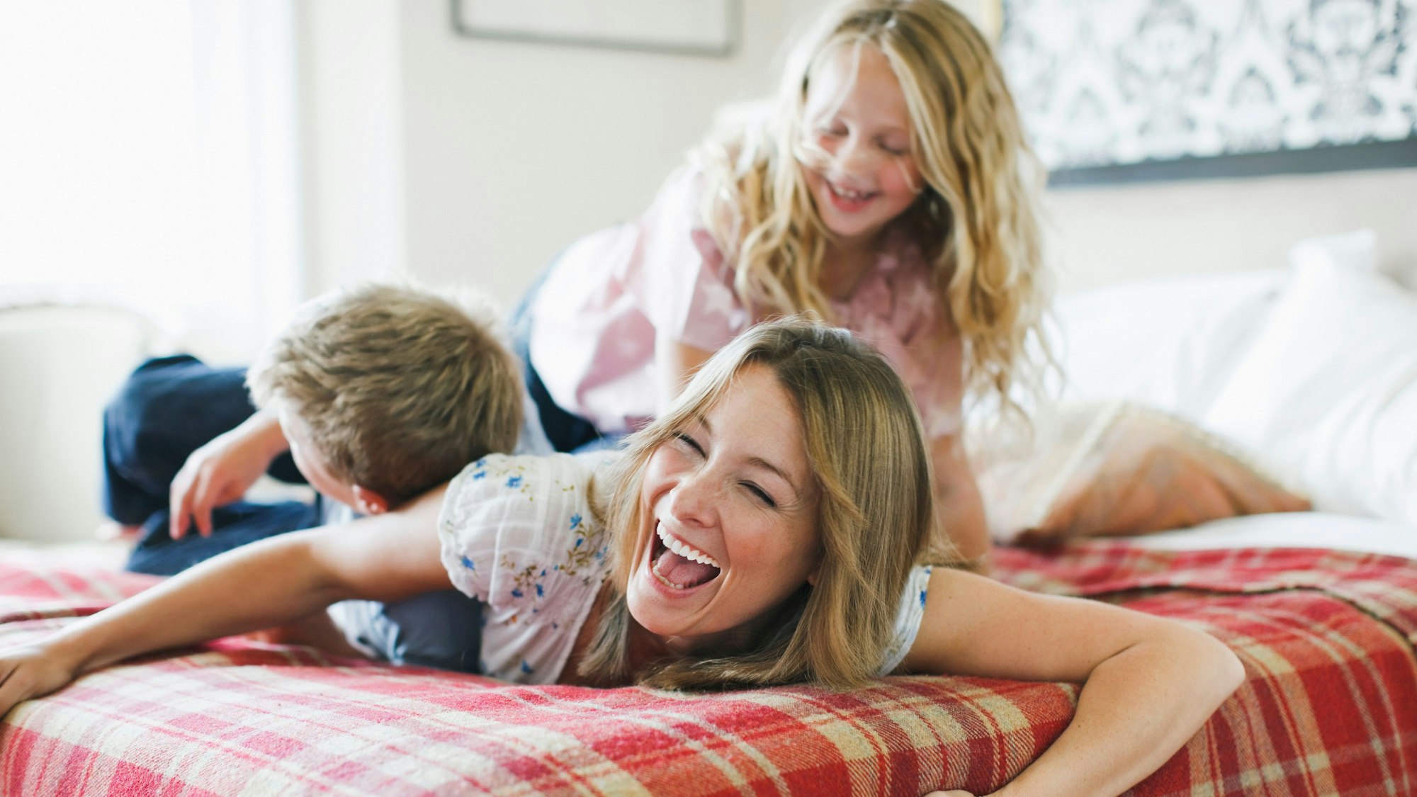 Mutter tobt mir ihren Kindern auf ddem Bett.