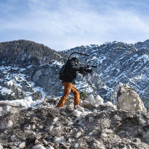 Eine Kamerafrau läuft über einen Haufen Schnee in den Bergen.