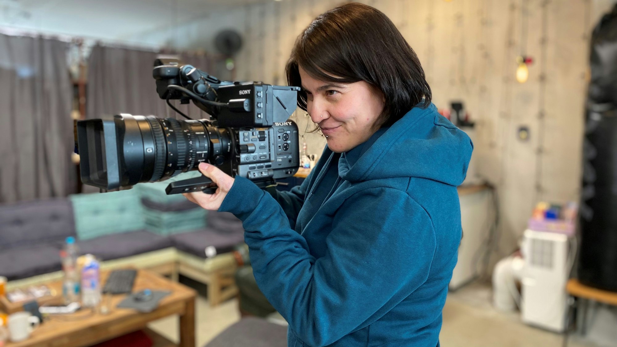 Die Kamerafrau hält in ihrem Studio eine Kamera.