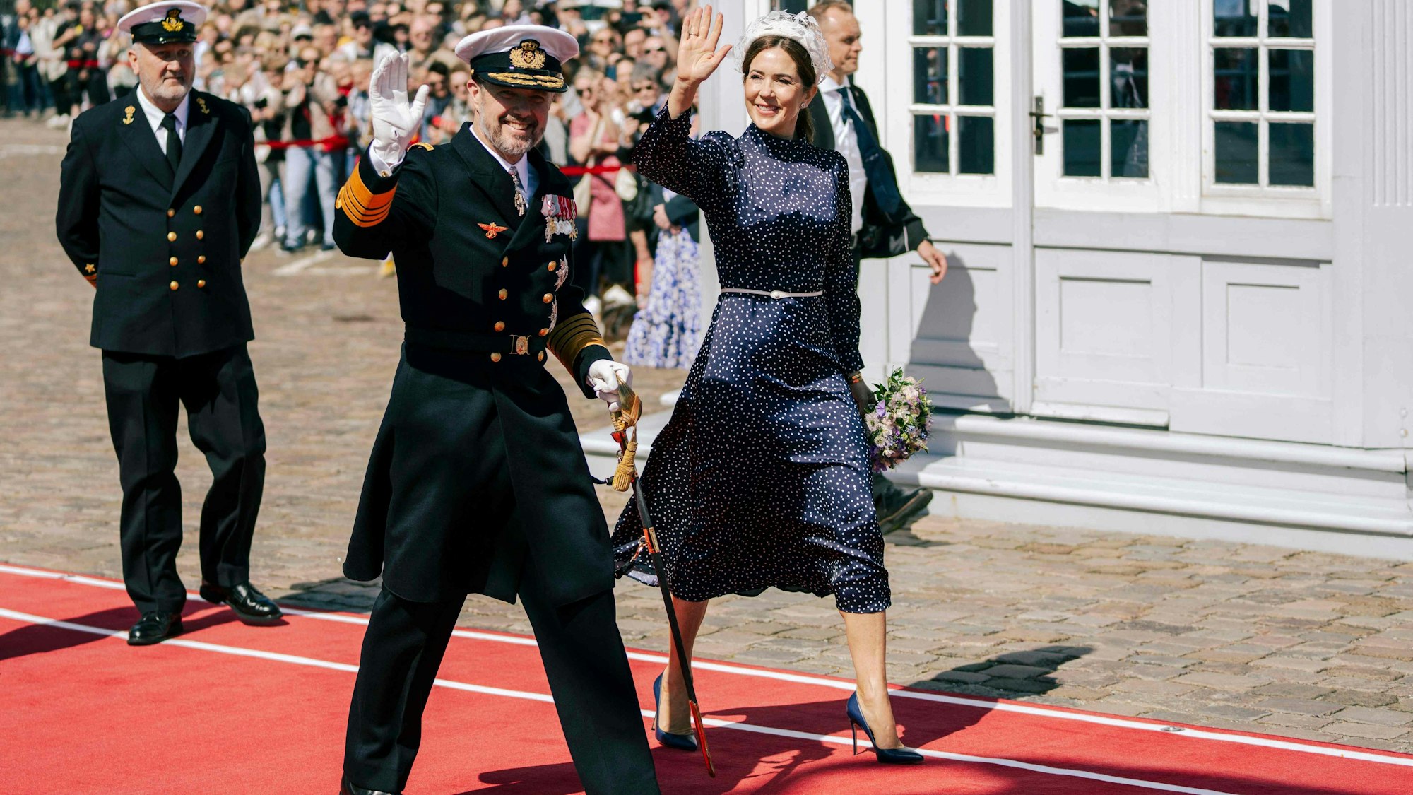 König Frederik X. und Königin Mary winken Schaulustigen zu, als sie an Bord des Schiffes Dannebrog im Hafen Nordre Toldbod in Kopenhagen gehen.