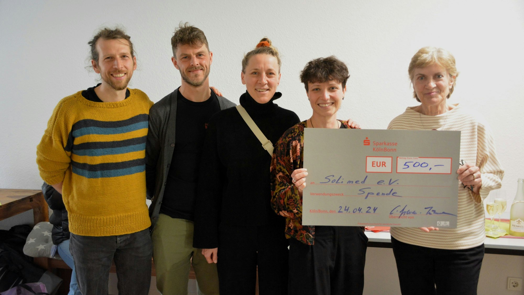 Vier Mitglieder des Kölner Vereins Solimed, zwei Männer und zwei Frauen, stehen neben der Bezirksbürgermeisterin Claudia Greven-Thürmer. Sie überreicht ihnen einen Scheck über 500 Euro. Foto von Stefan Rahmann.