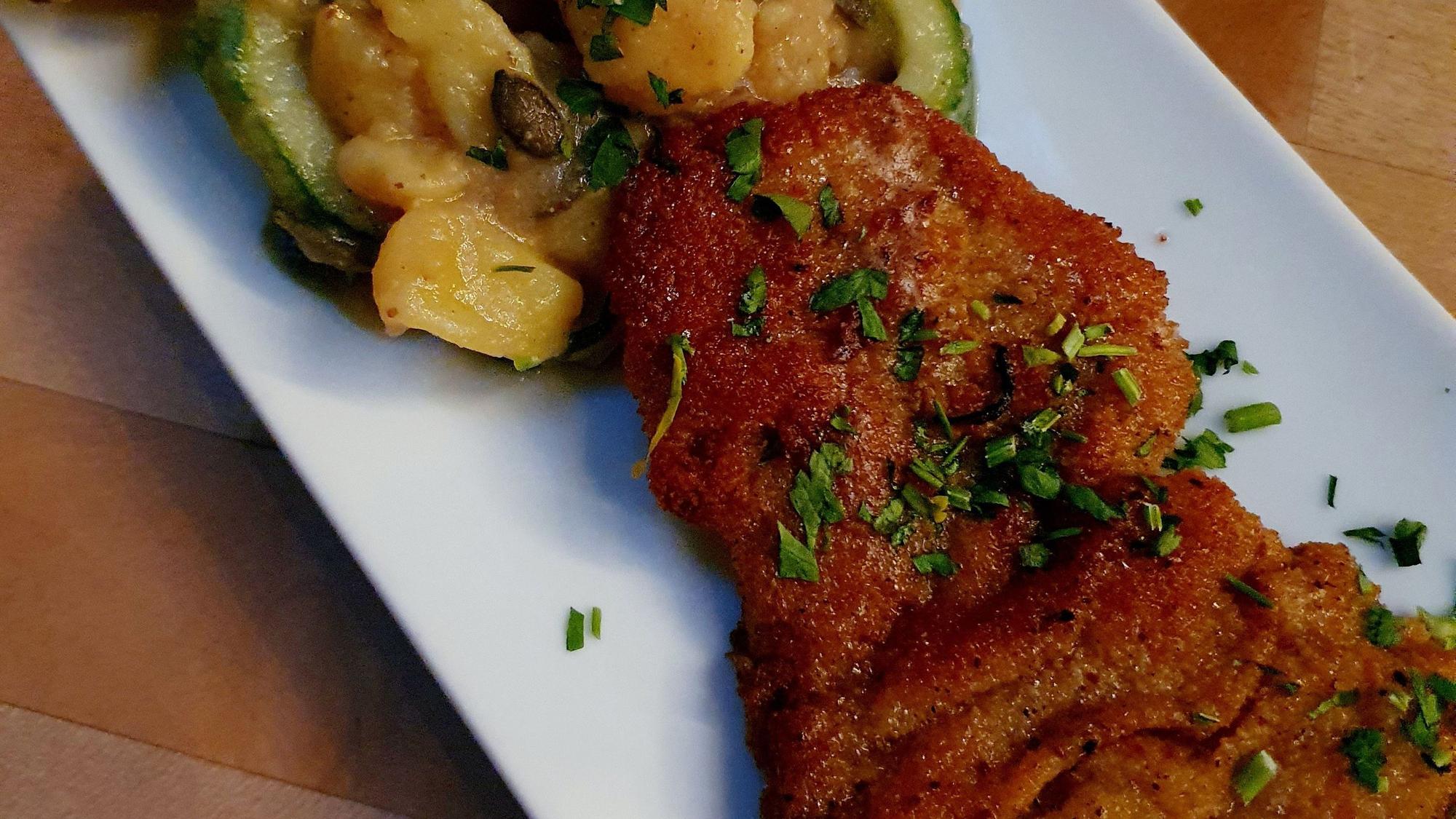 ein Teller mit Schnitzel und Kartoffelsalat im Meer sehen.