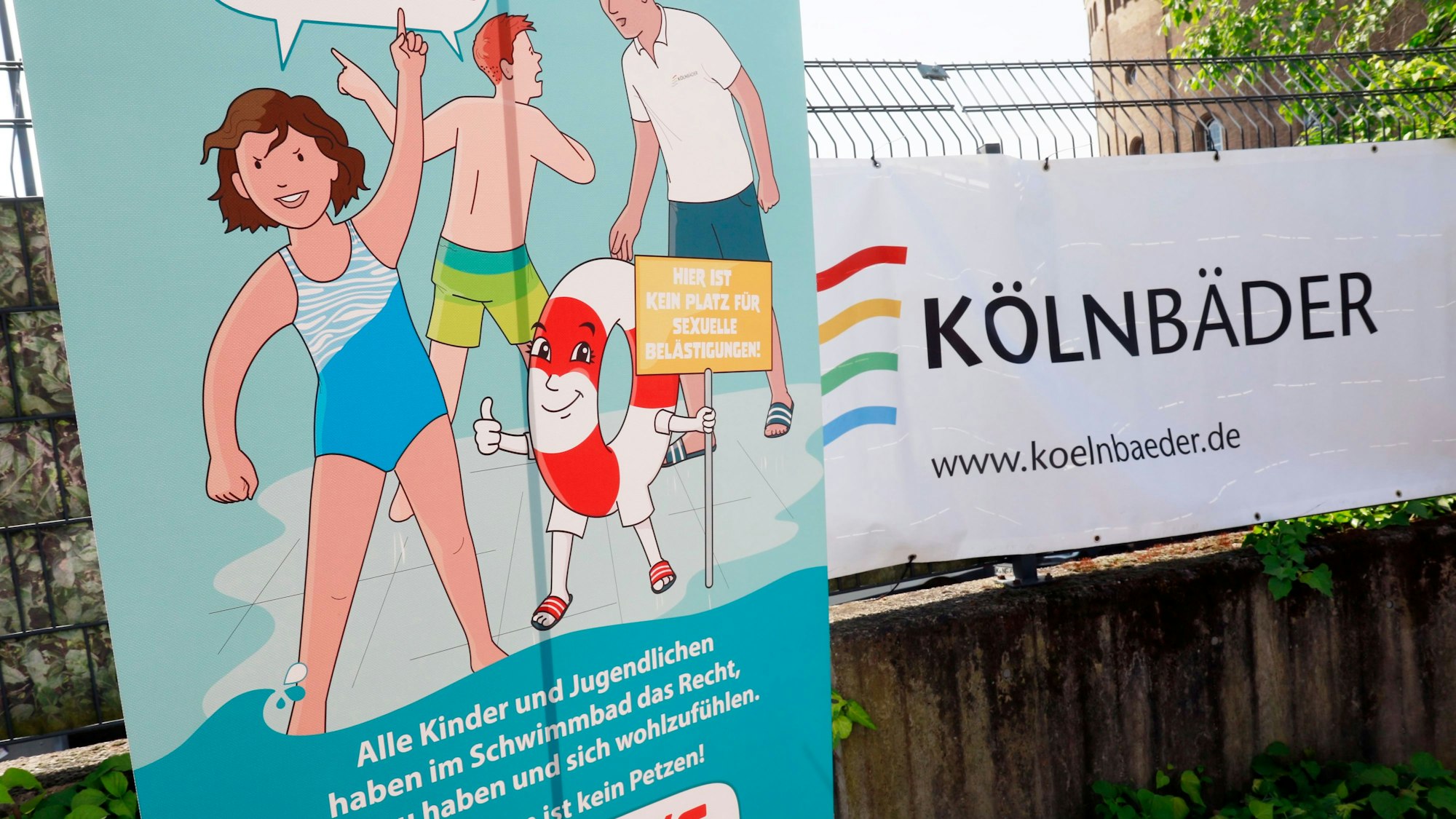 Am Zaun des Kölner Agrippa-Bads hängt das Plakat der „Ich sag’s!“-Kampagne zum Schutz vor sexualisierter Gewalt im Schwimmbad. Daneben hängt ein Bannder der Köln-Bäder.