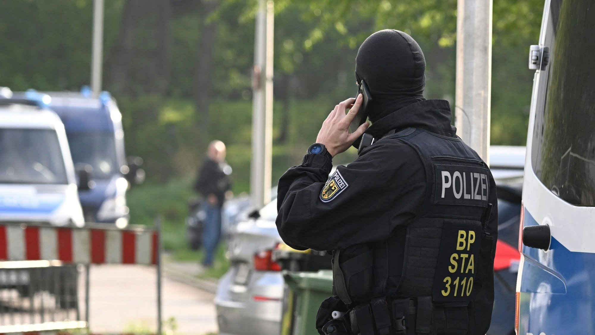 Ein Polizist mit Sturmhaube telefoniert mit einem Handy.