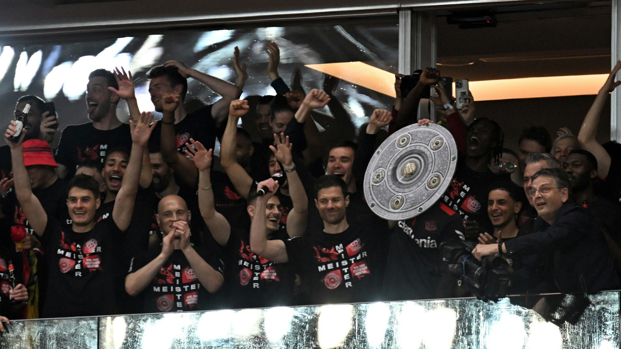 Leverkusens Spieler feiern den Gewinn der Deutschen Meisterschaft. Trainer Xabi Alonso hält eine Meisterschale in die Höhe.