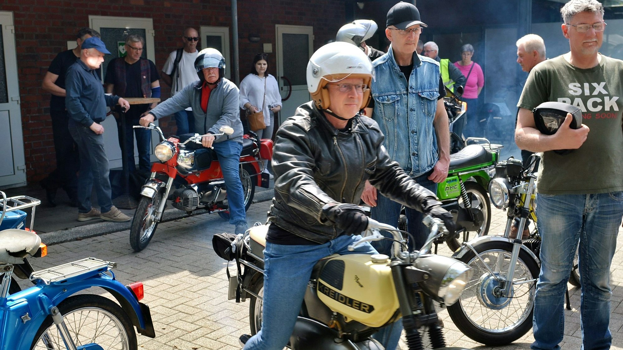 Das Foto zeigt mehrere Teilnehmer, ein Mann sitzt auf einer Kreidler.