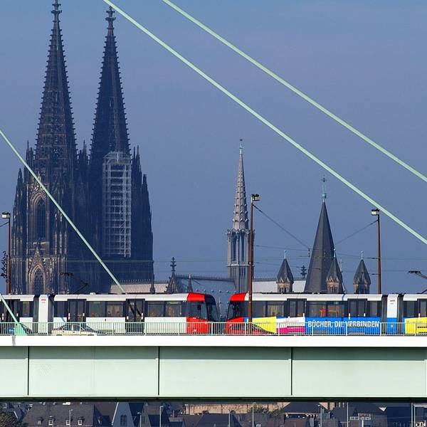 Zu sehen ist eine Stadtbahn der KVB in der Seitenansicht, die über die Severinsbrücke fährt. Im Hintergrund ist der Kölner Dom zu sehen.