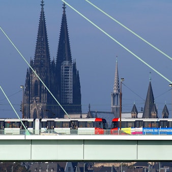Zu sehen ist eine Stadtbahn der KVB in der Seitenansicht, die über die Severinsbrücke fährt. Im Hintergrund ist der Kölner Dom zu sehen.