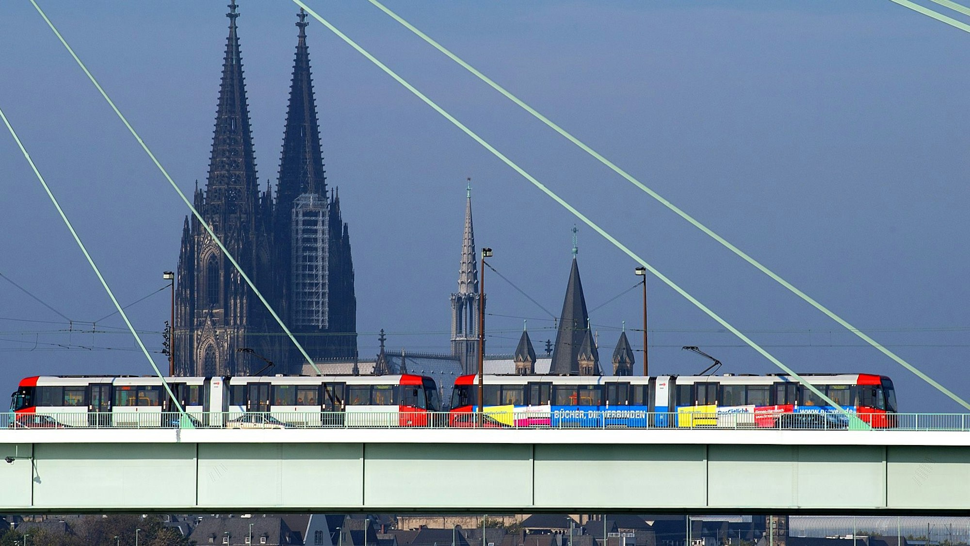 Zu sehen ist eine Stadtbahn der KVB in der Seitenansicht, die über die Severinsbrücke fährt. Im Hintergrund ist der Kölner Dom zu sehen.