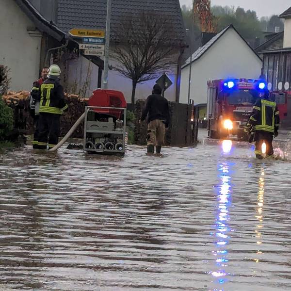 Das Bild zeigt eine überflutete Straße in Schmidtheim. Die Feuerwehr pumpt das Wasser ab.