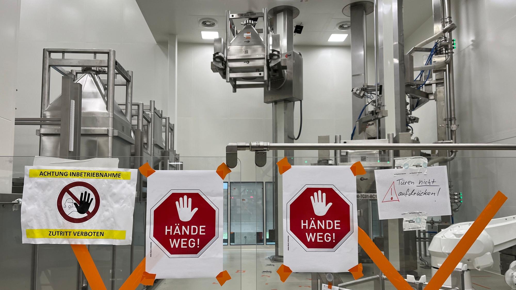 Blick auf einen Teil der neuen Tablettenproduktion von Bayer am 3. Mai 2024. Im Vordergrund hängen Schilder mit der Aufschrift „Hände weg“.