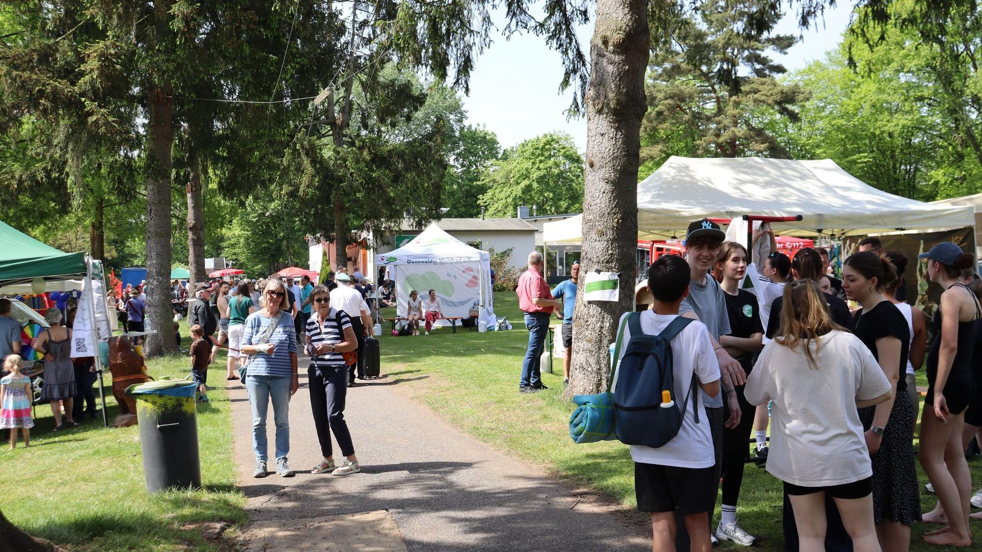 Besucher sehen sich bei sonnigem Wetter auf dem Maifest im Waldbad Dünnwald um. Foto von Uwe Schäfer.