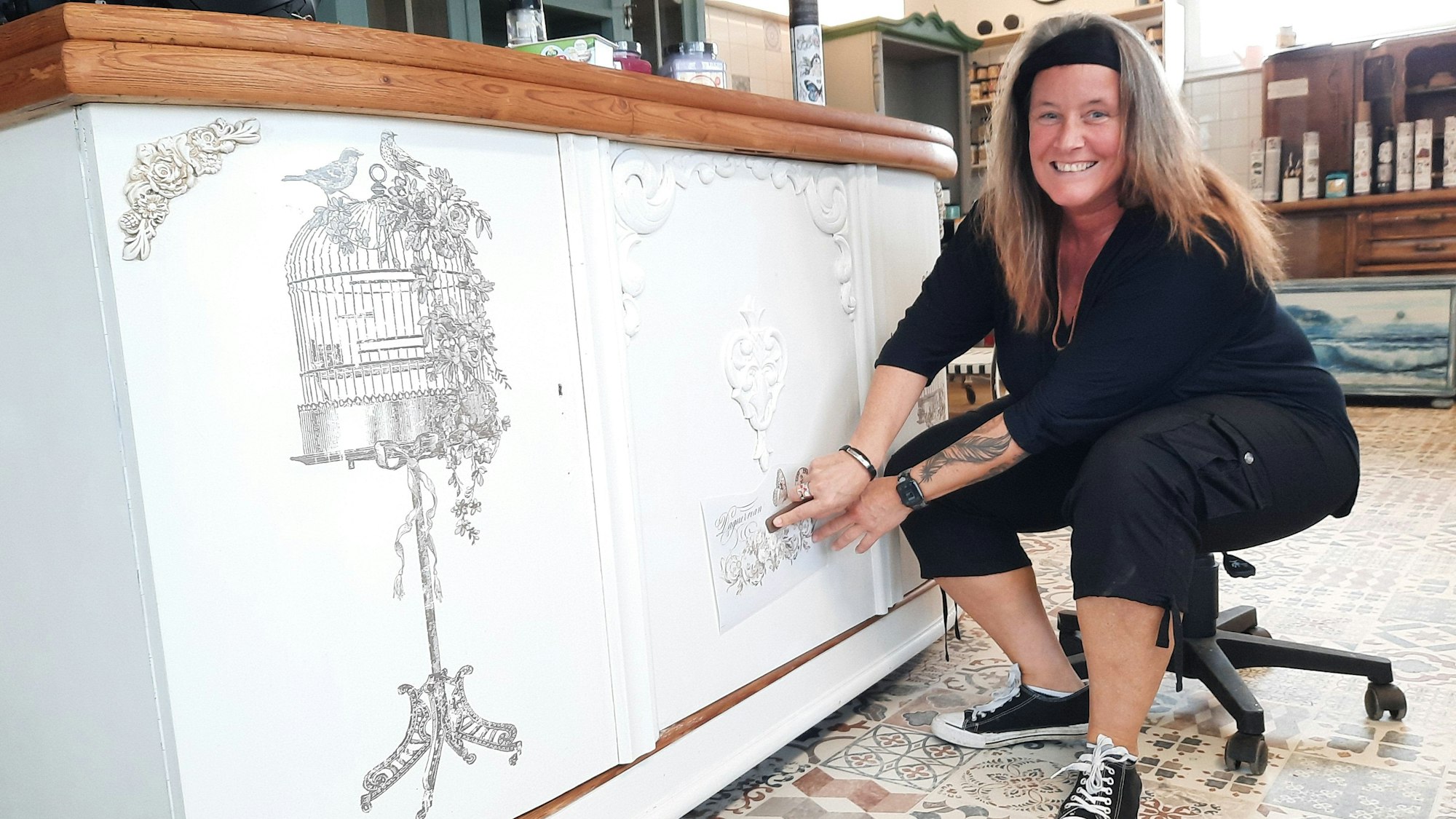 Claudia Schreiber sitzt vor einem Schrank und arbeitet an der weißen Holzoberfläche.
