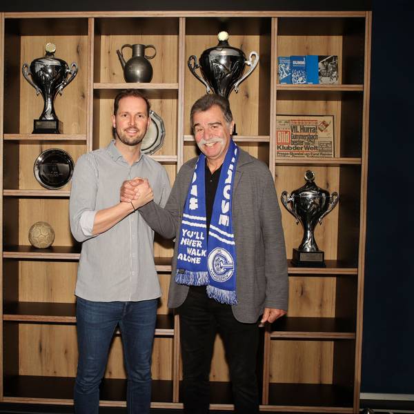 Heiner Brand und Geschäftsführer Christoph Schindler stehen vor dem Trophäenschrank des VfL Gummersbach.