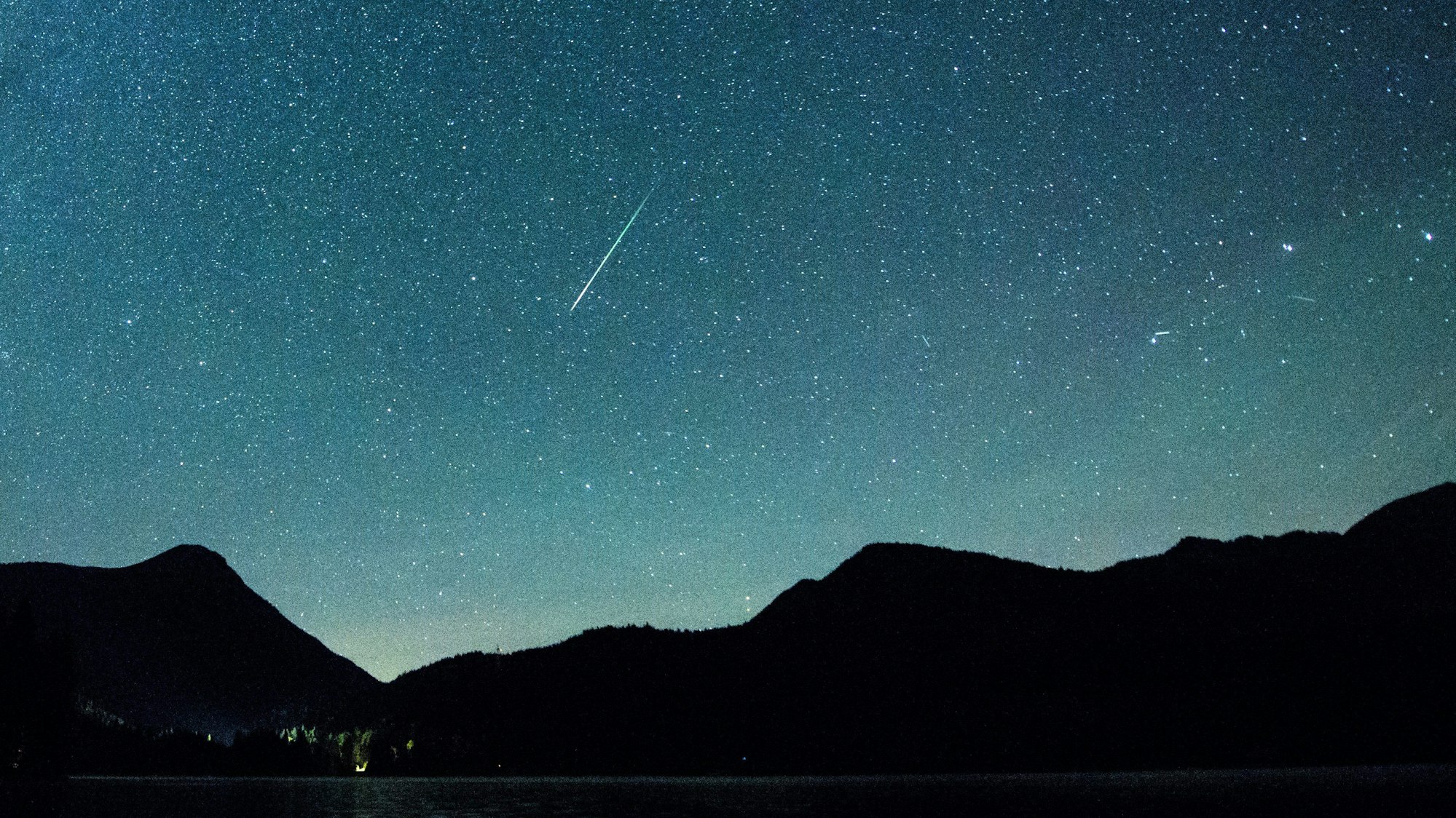 Bayern, Einsiedl: Eine Sternschnuppe leuchtet neben der Milchstraße am Himmel über dem Walchensee. (Archivbild)