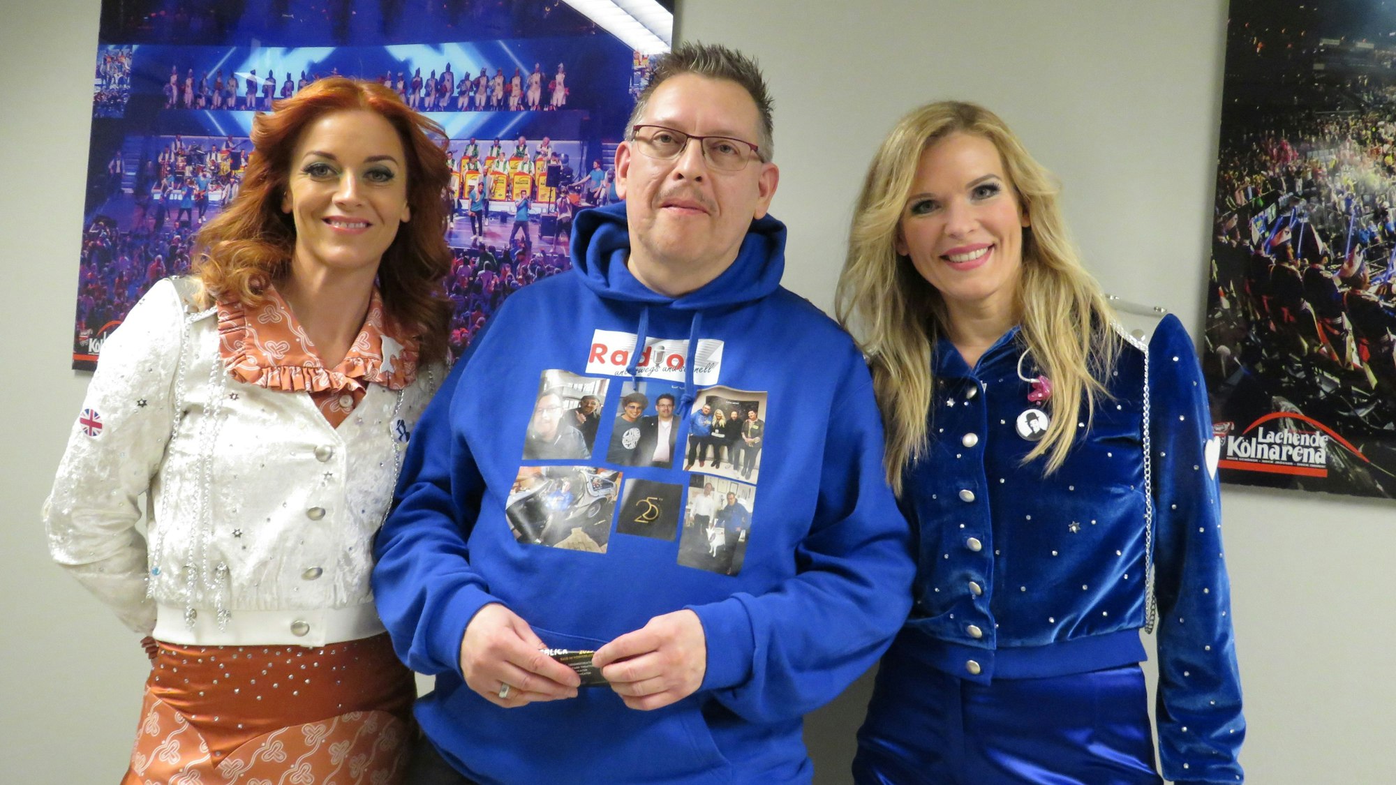 Zwei Damen mit einem Herrn in der Mitte.