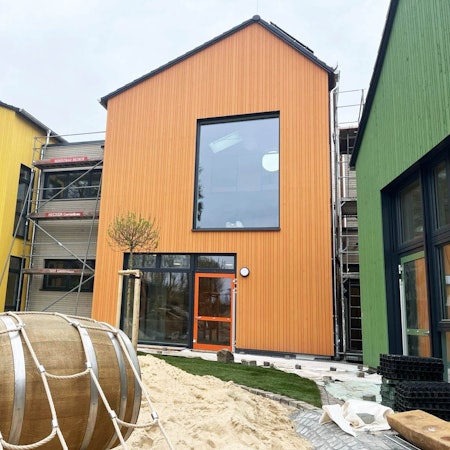 Bunte Giebelhäuser stehen inmitten von Baumaterialien.