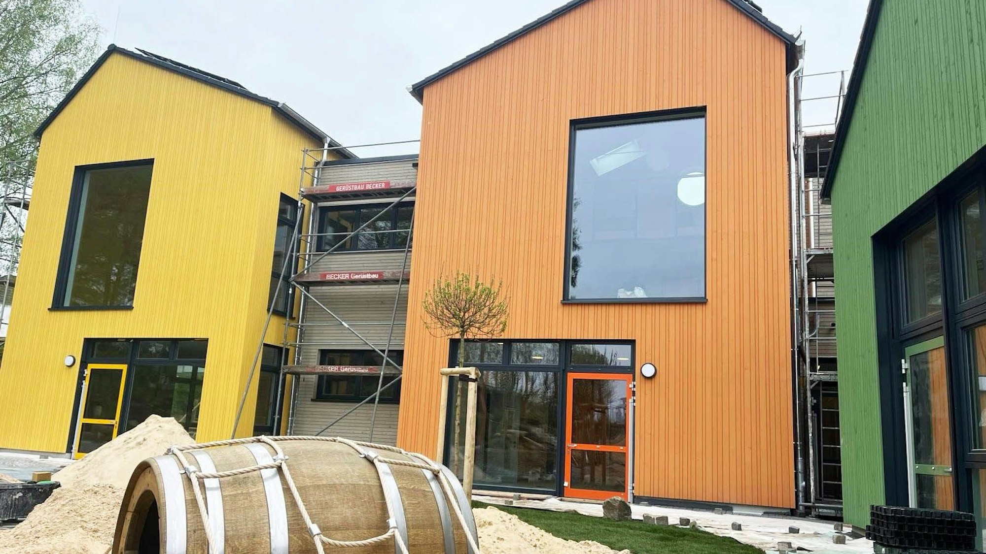 Bunte Giebelhäuser stehen inmitten von Baumaterialien.