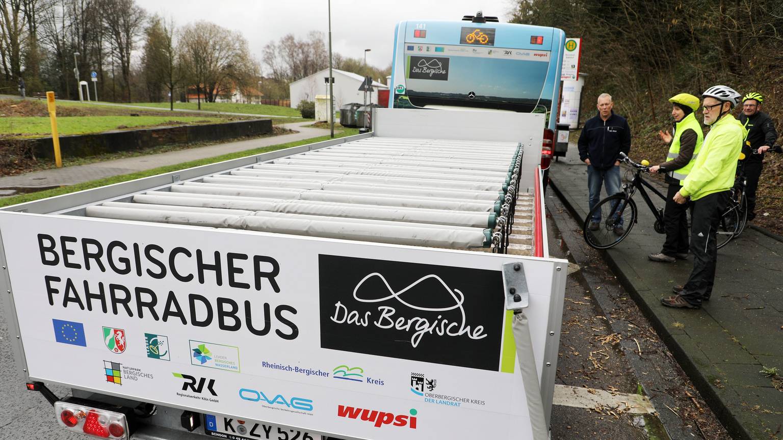 Ein Fahrradanhänger hinter einem Bergischen Fahrradbus steht an einer Haltestelle in Burscheid.