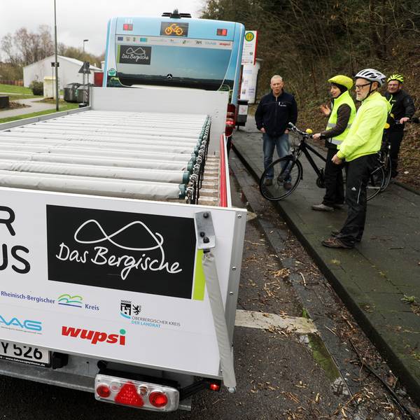 Ein Fahrradanhänger hinter einem Bergischen Fahrradbus steht an einer Haltestelle in Burscheid.