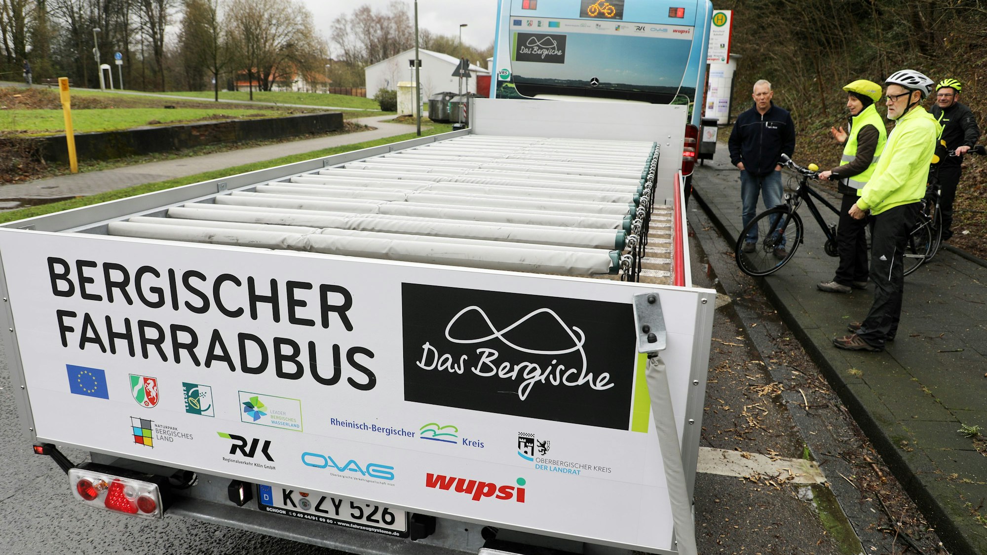 Eine Frau und ein Mann stellen ihre Fahrräder auf einen Anhänger.