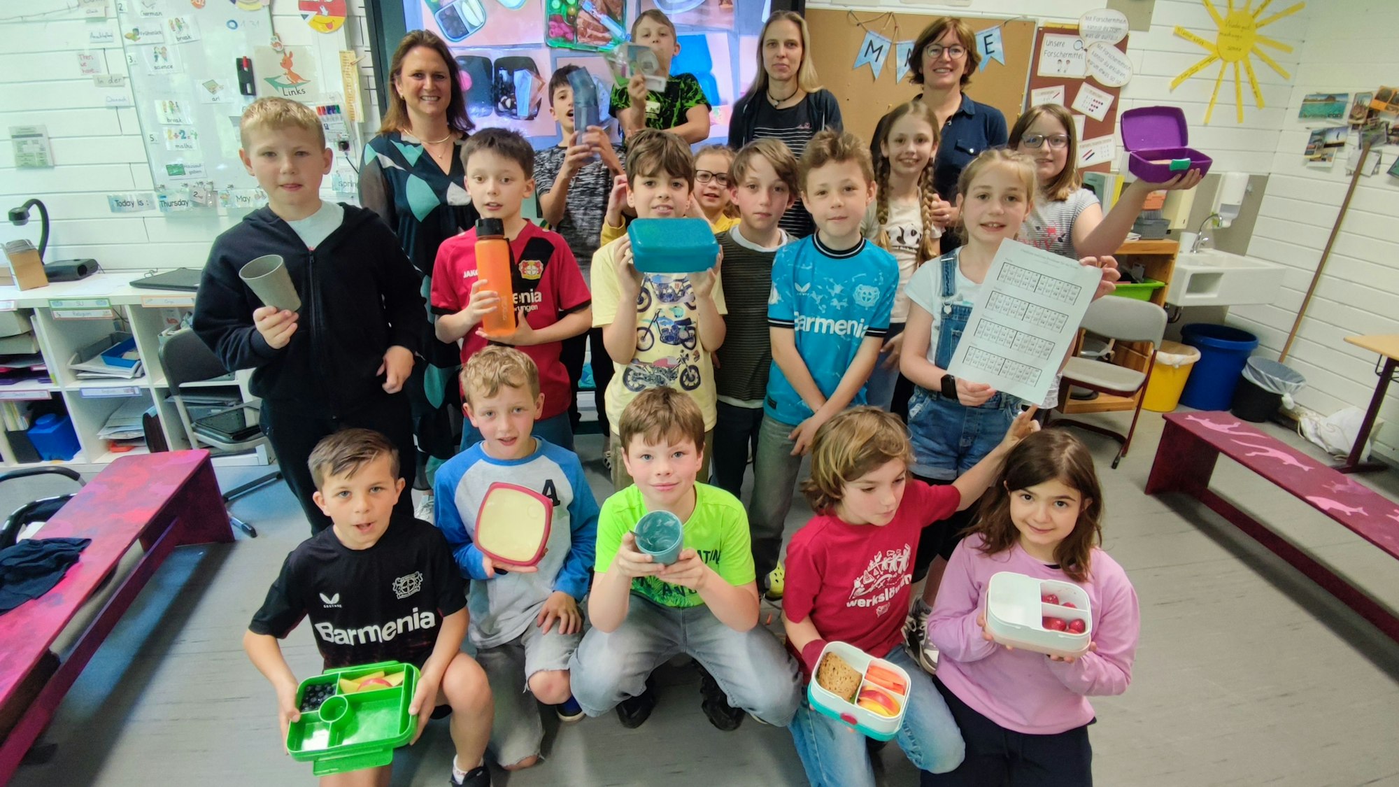 Eine Schulklasse posiert mit Brotdosen für ein Foto.