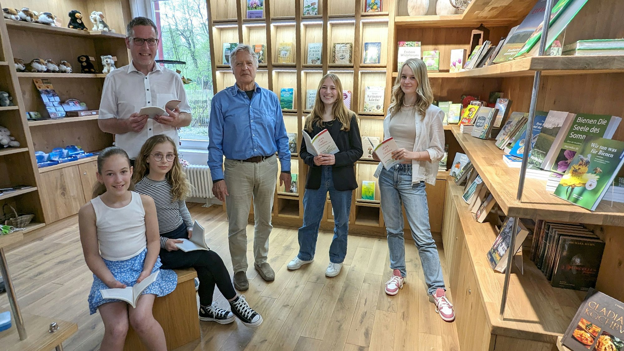 Bürgermeister Norbert Crump (l.), Organisator Jochen Starke und vier Preisträgerinnen des Vorjahres vor Regalen, in denen sich verschiedene Bücher befinden.