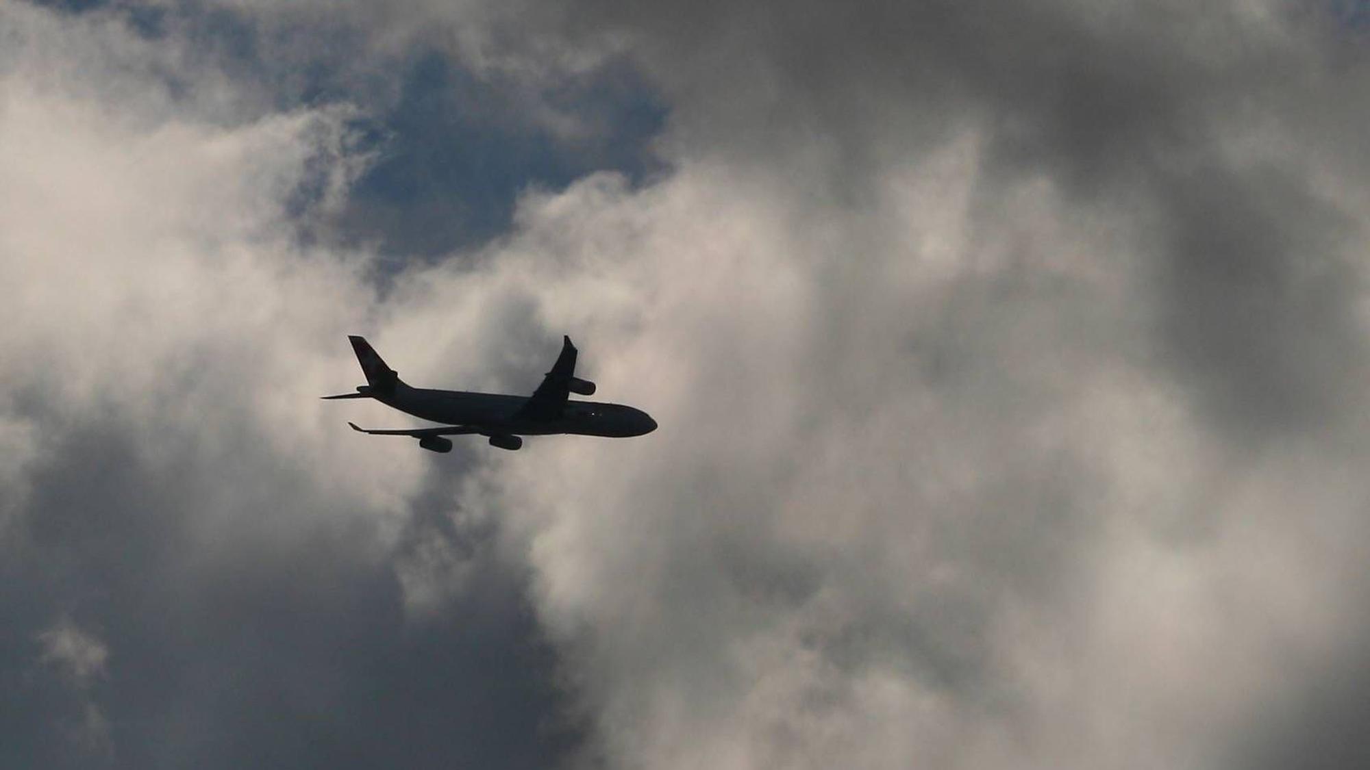 Ein Flugzeug fliegt inmitten eines Unwetters am Himmel in mehrere Gewitterwolken hinein. (Symbolbild)