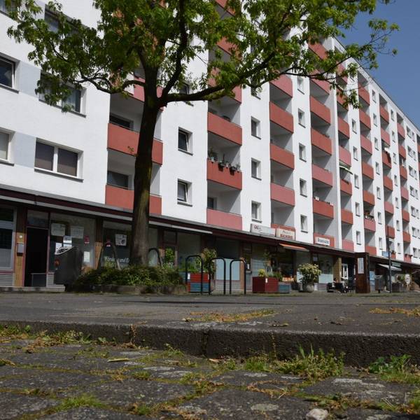 Blick auf den Piccoplatz in Köln-Holweide, der nicht barrierefrei ist. Im Hintergrund ist ein Hochhaus zu sehen. Foto von Rika Kulschewski.