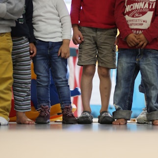 Acht Kinder stehen in einer Reihe, einige tragen keine Schuhe, das Bild steht symbolisch für die steigende Kinderarmut und die Hilfe, auf die junge Menschen angewiesen sind.