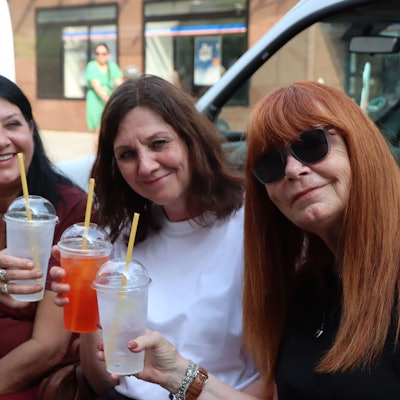 Zu sehen sind drei Besucherinnen, die einen Cocktail trinken.