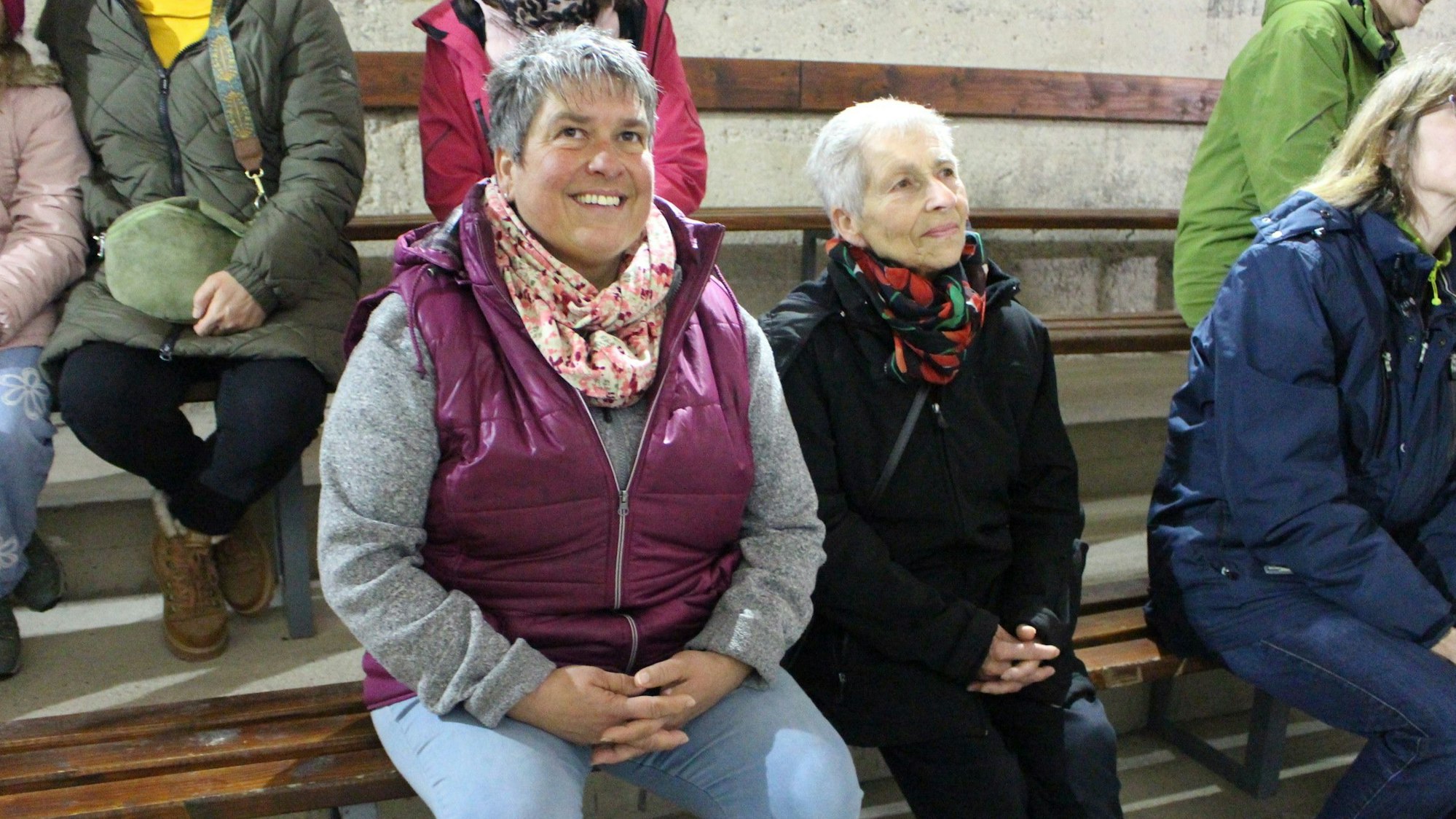 Die beiden Frauen sitzen auf einer Bank und lauschen, was der Leiter der Führung durch die Talsperre erklärt.