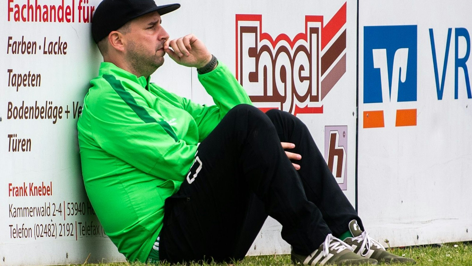 Das Bild zeigt Sötenichs Trainer an einer Bande sitzend.