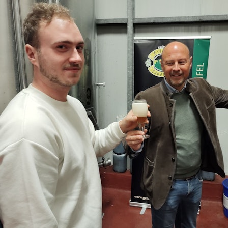 Johannes Schweizer reicht einem Besucher ein gezapftes Bier.