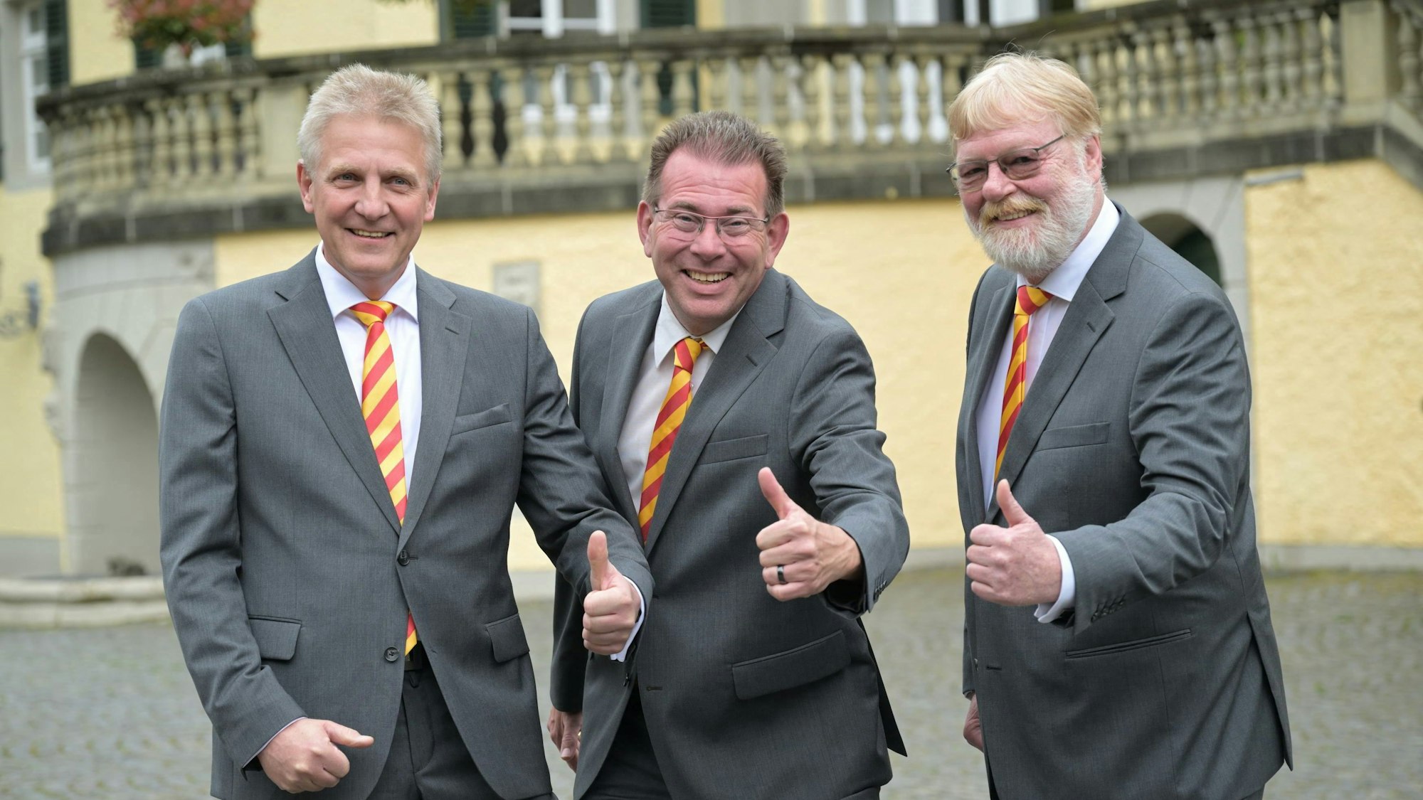 Die drei Männer stehen nebeneinander und halten die Daumen hoch.