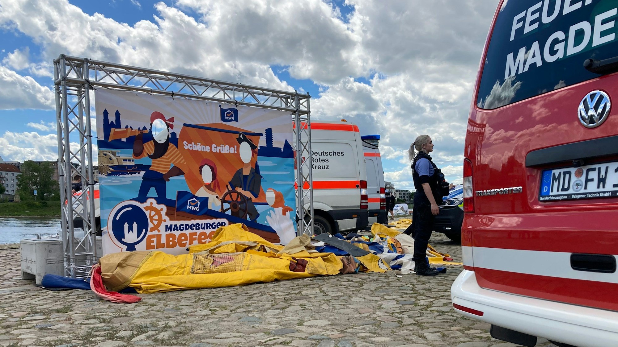 Einsatzfahrzeuge stehen am Elbufer neben einer zusammengefallenen Hüpfburg.