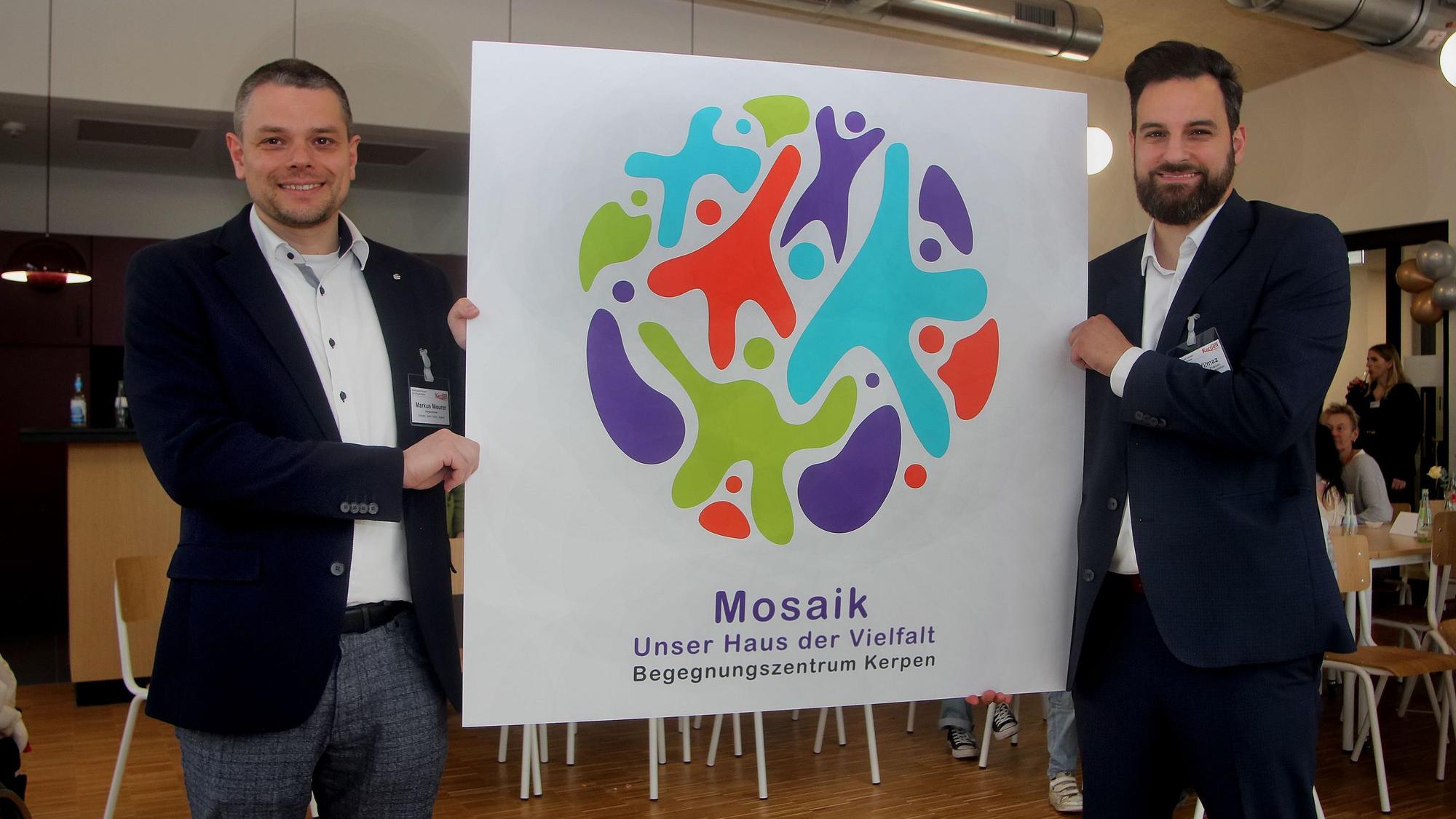 Beigeordneter Markus Meurer (l.) und Dezernent Cem Yilmaz präsentieren das von Kerpener Schülerinnen und Schülern entwickelte Mosaik-Logo.