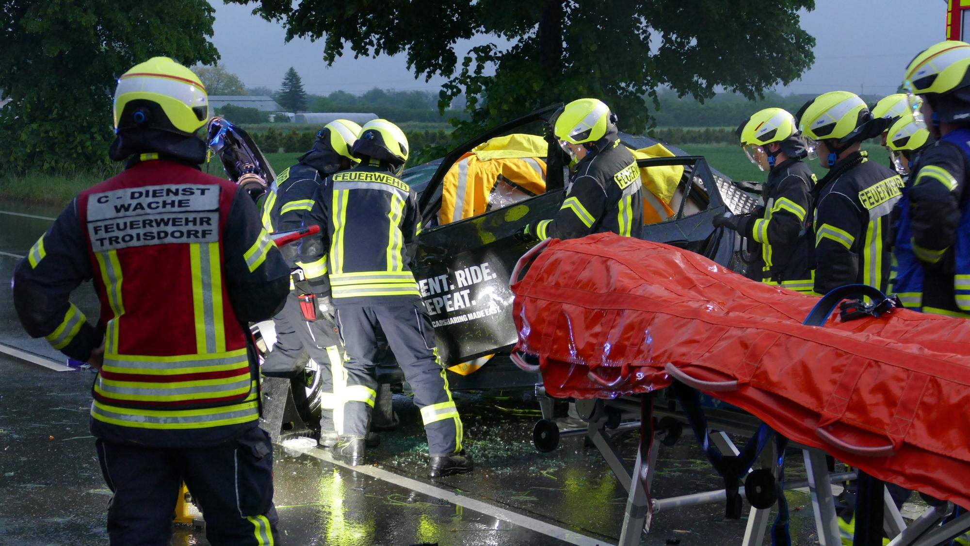 Feuerwehrleute schneiden eine Tür an einem Auto weg.