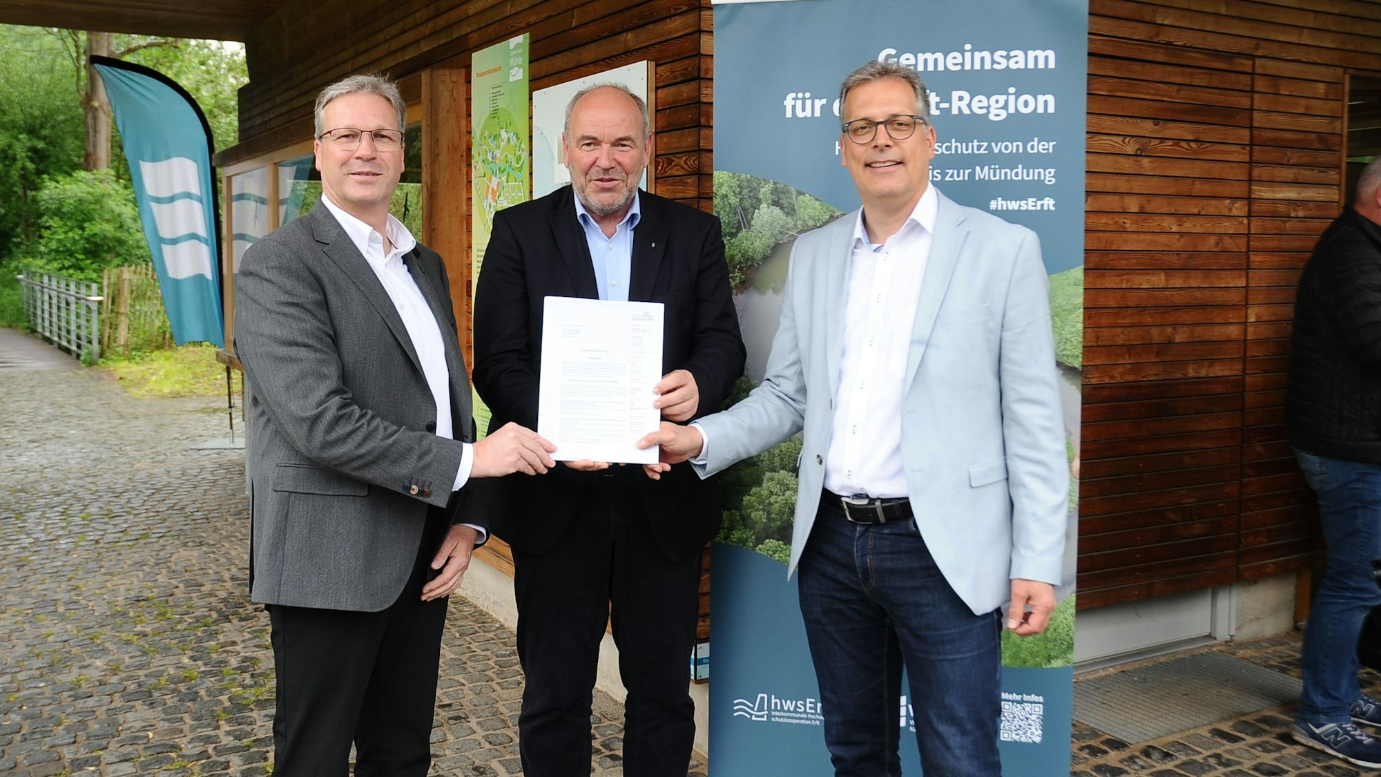 Drei Männer halten einen Bescheid.