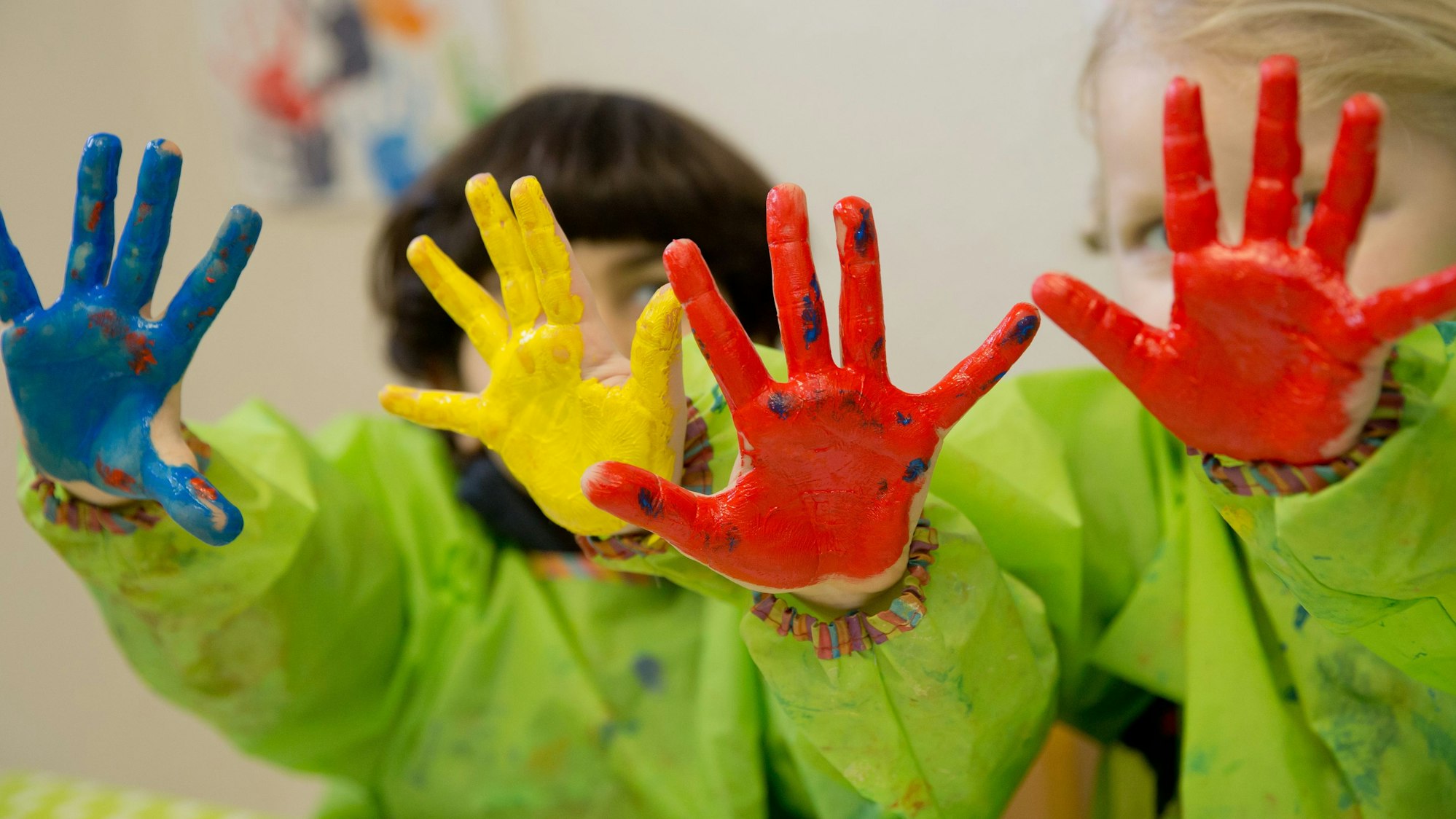 Zwei Kinder spielen mit Fingerfarben im Atelier eines Kindergartens.