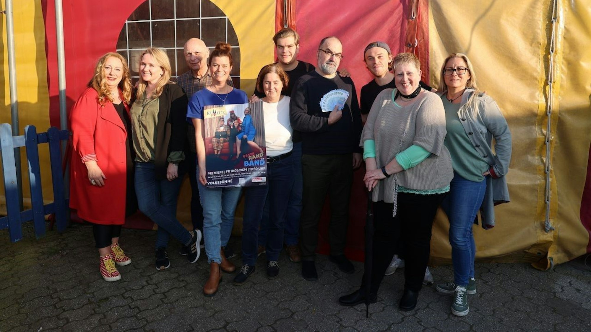 10 Menschen stehen vor einem Zirkuszelt
